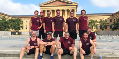Eleven men are pictured in front of the Philadelphia Museum of Art.